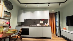 Una cocina moderna con una isla central, una mesa de comedor con sillas, un reloj y un televisor en la pared.
