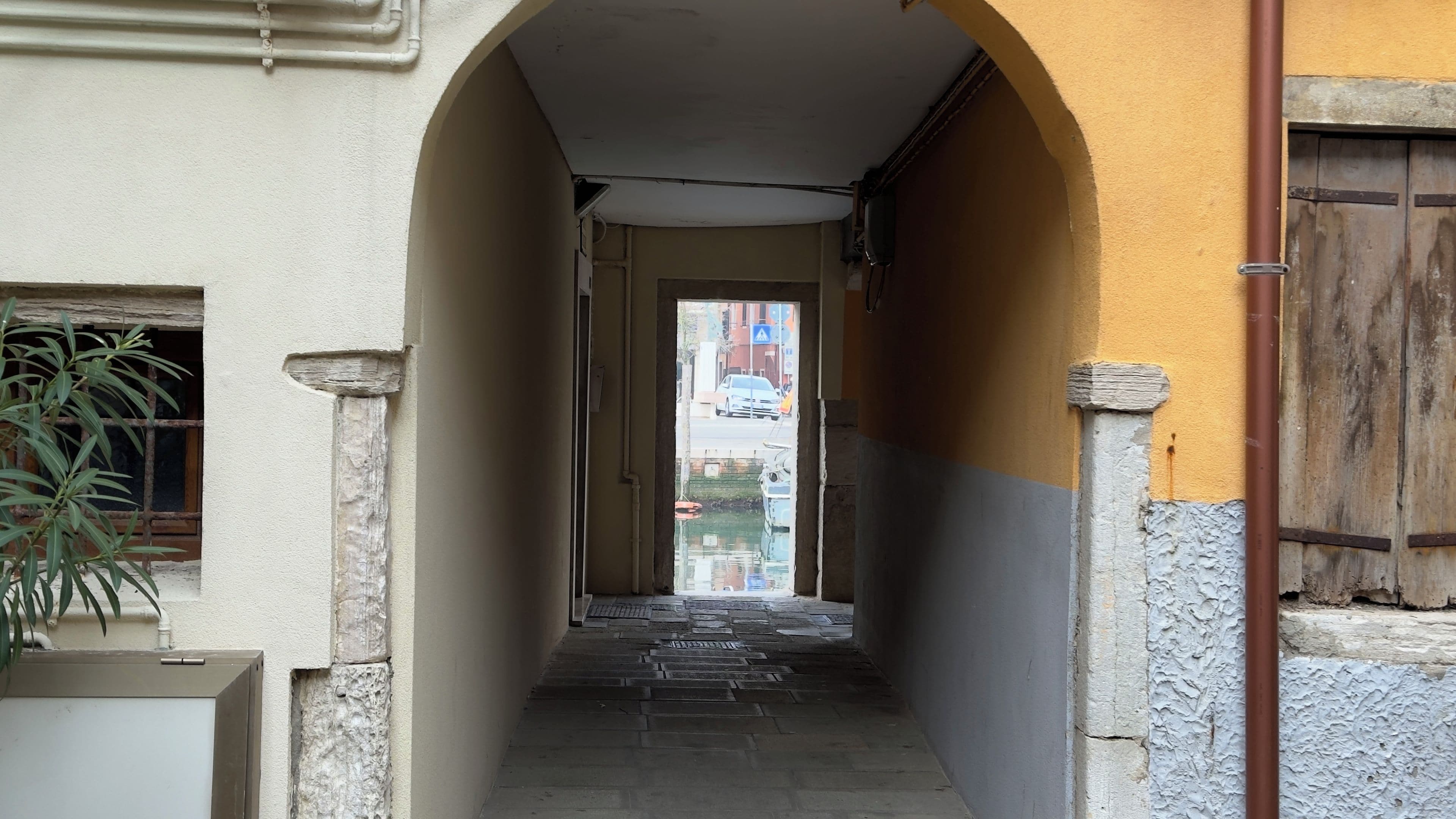 A narrow corridor with a tiled floor leading to a doorway.