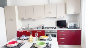 Una cocina moderna con una mesa de comedor para dos personas, estufa a gas, microondas y una televisión pequeña.