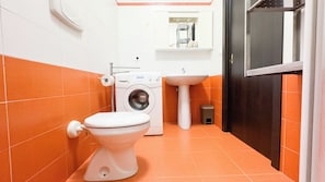 Casa de banho pequena com sanita, máquina de lavar roupa e lavatório.