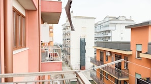 Um edifício residencial com varandas, uma escadaria central e vista para prédios vizinhos.