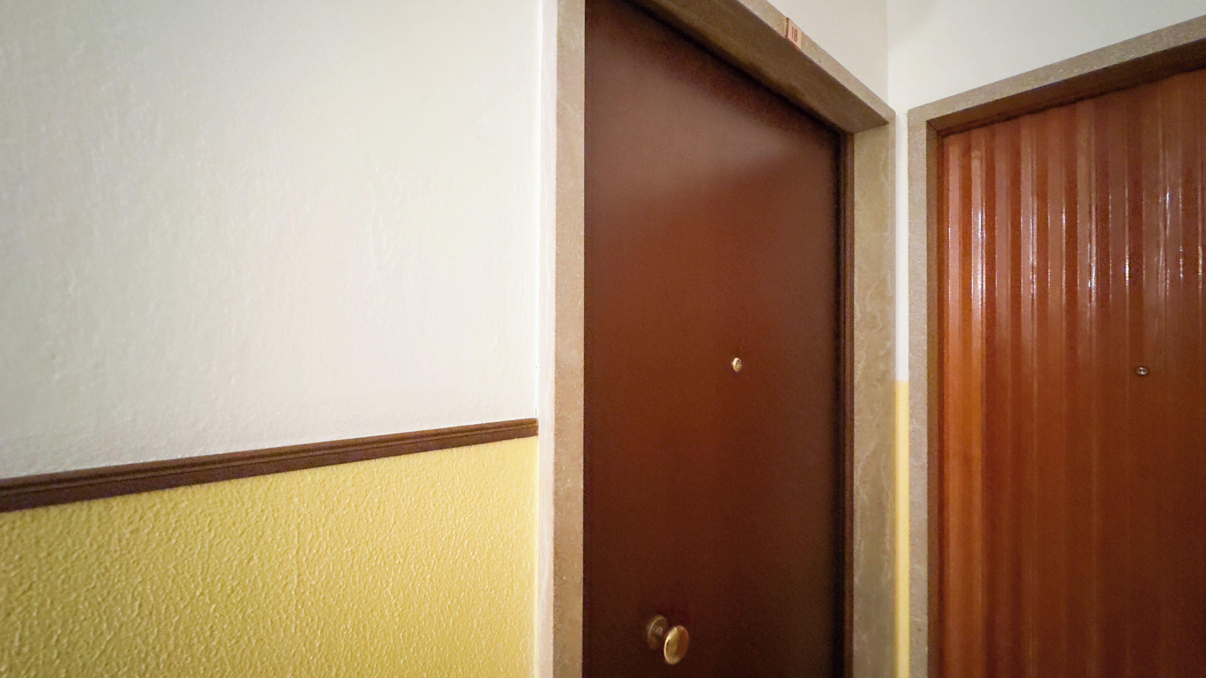 Una puerta con pomo de latón, junto a una pared con una decoración amarilla y blanca.