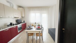 Cozinha compacta com área de refeições, um sofá e uma porta que dá para outro cômodo.