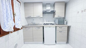 Een kleine keuken met een gasfornuis, een magnetron en een vaatwasser.