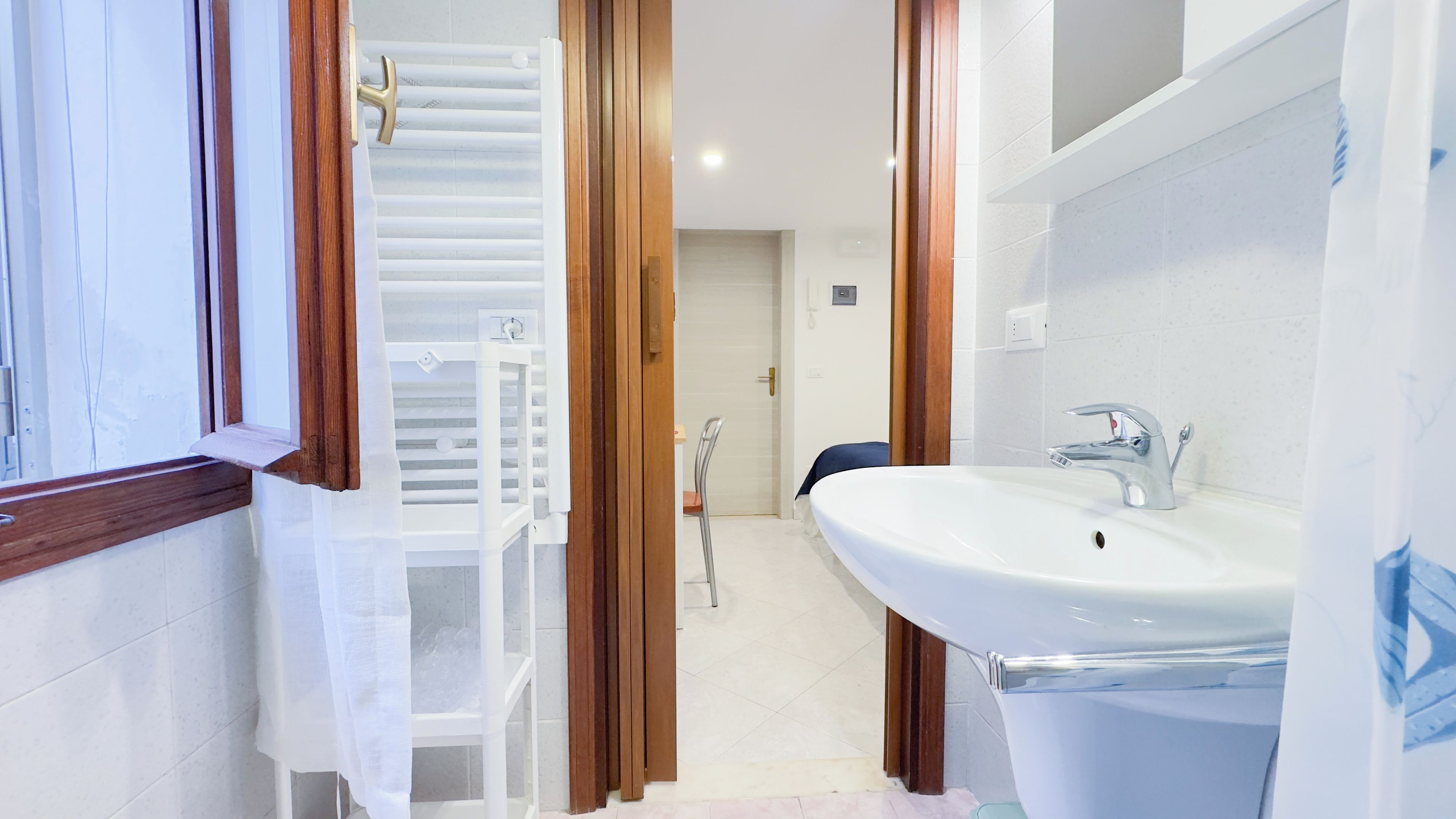 Une salle de bain avec un lavabo blanc, un miroir et une douche.