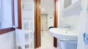 Une salle de bain avec un lavabo blanc, un miroir et une douche.