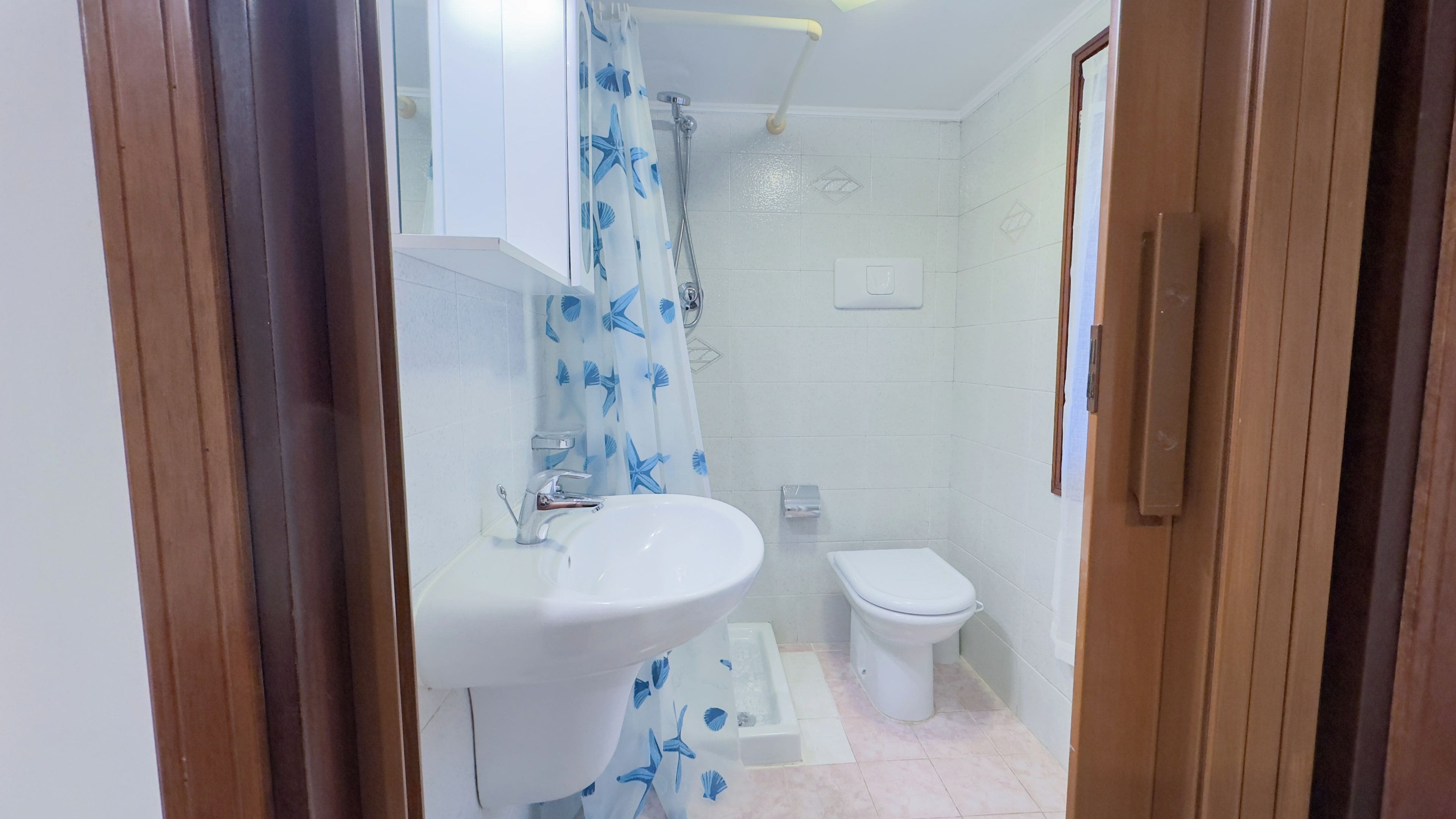 A bathroom with a shower, a sink, and a toilet.