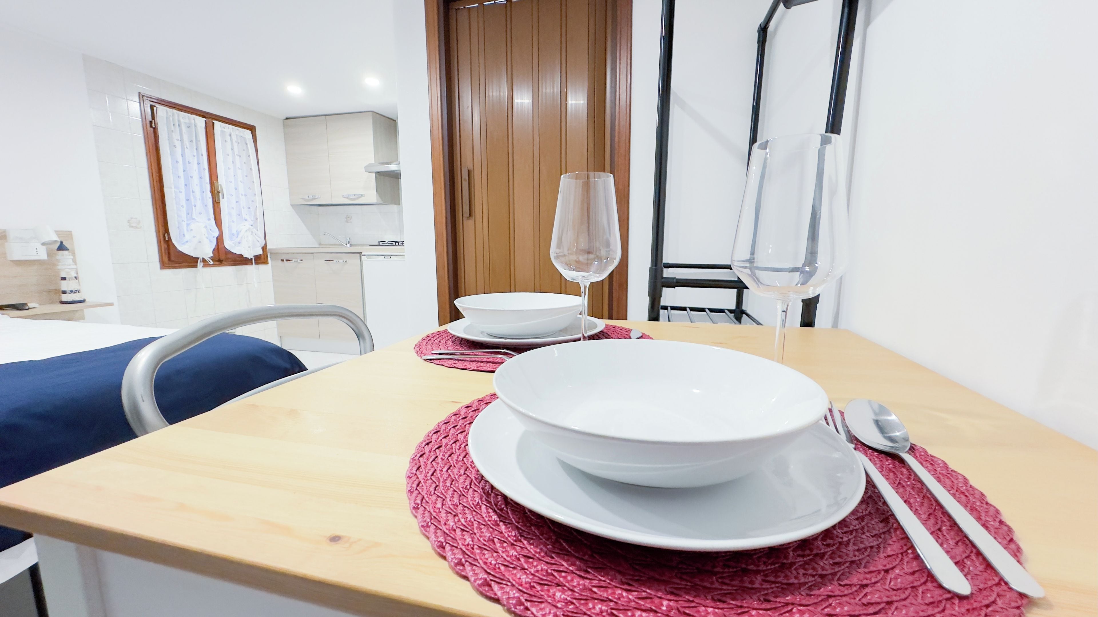 A neatly arranged dining table with white plates, a glass of water, and a fork and spoon.