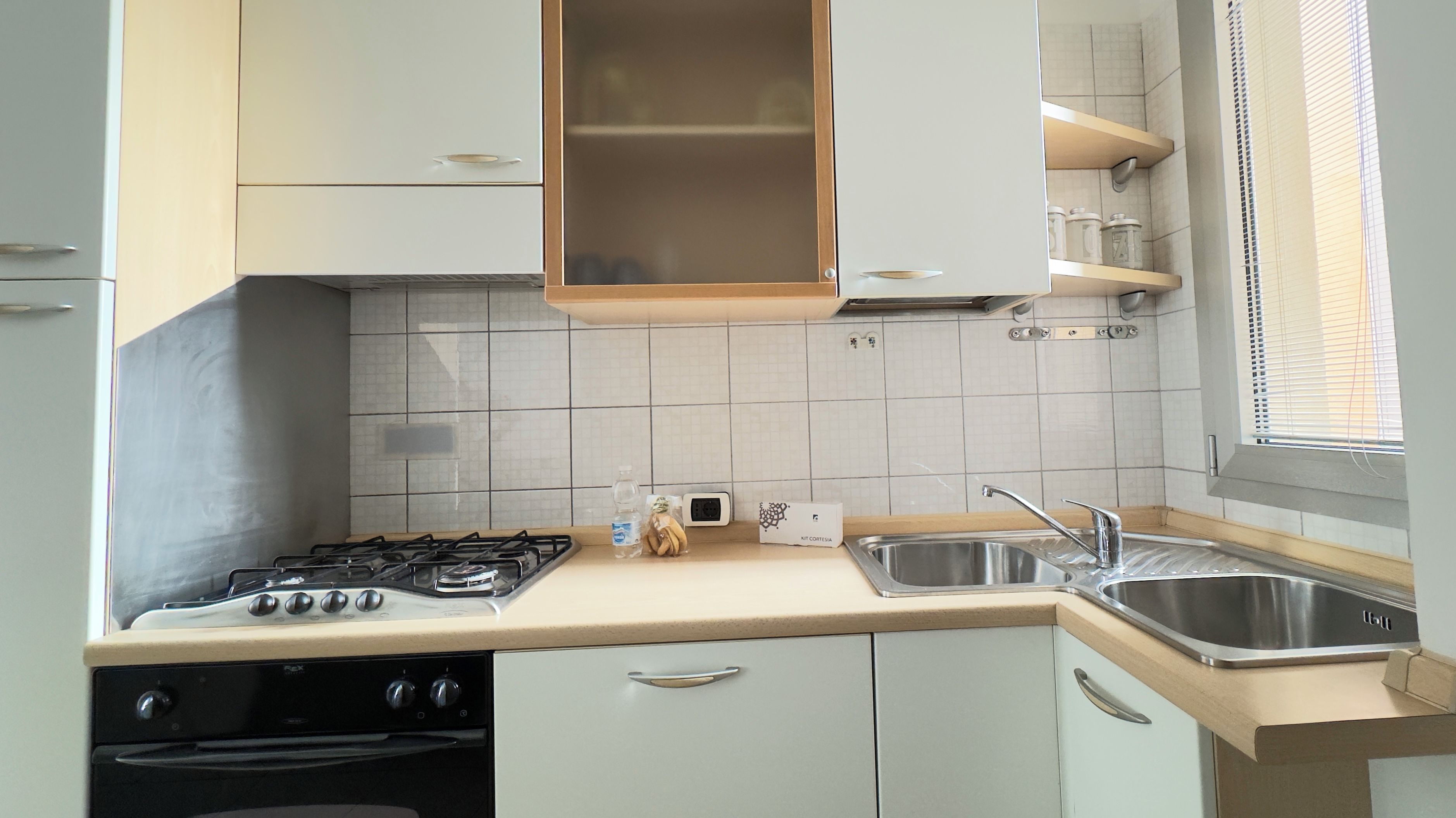 A kitchen with a gas stove, oven, sink, and cabinets.