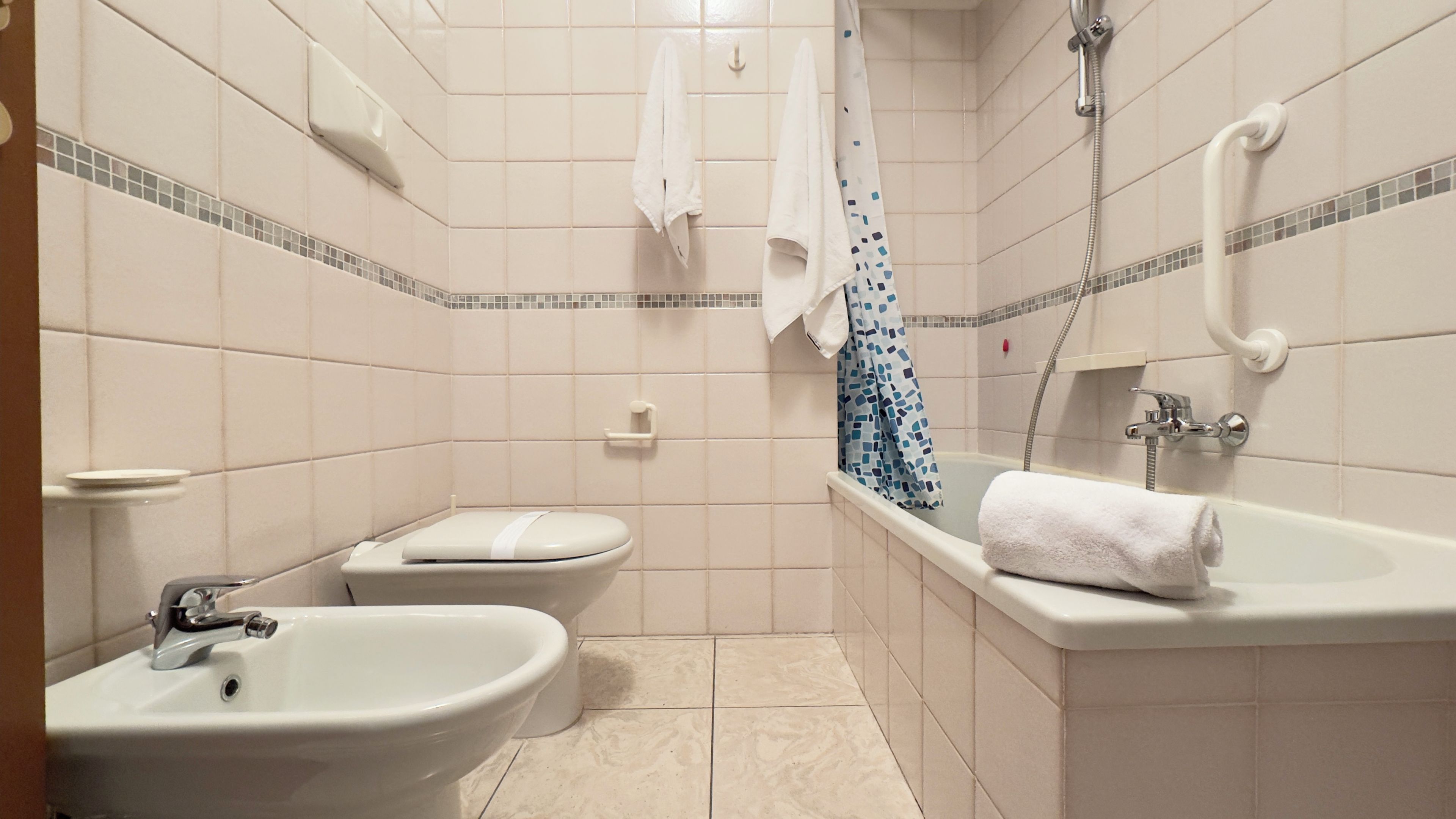 A bathroom with a toilet, bidet, and bathtub.