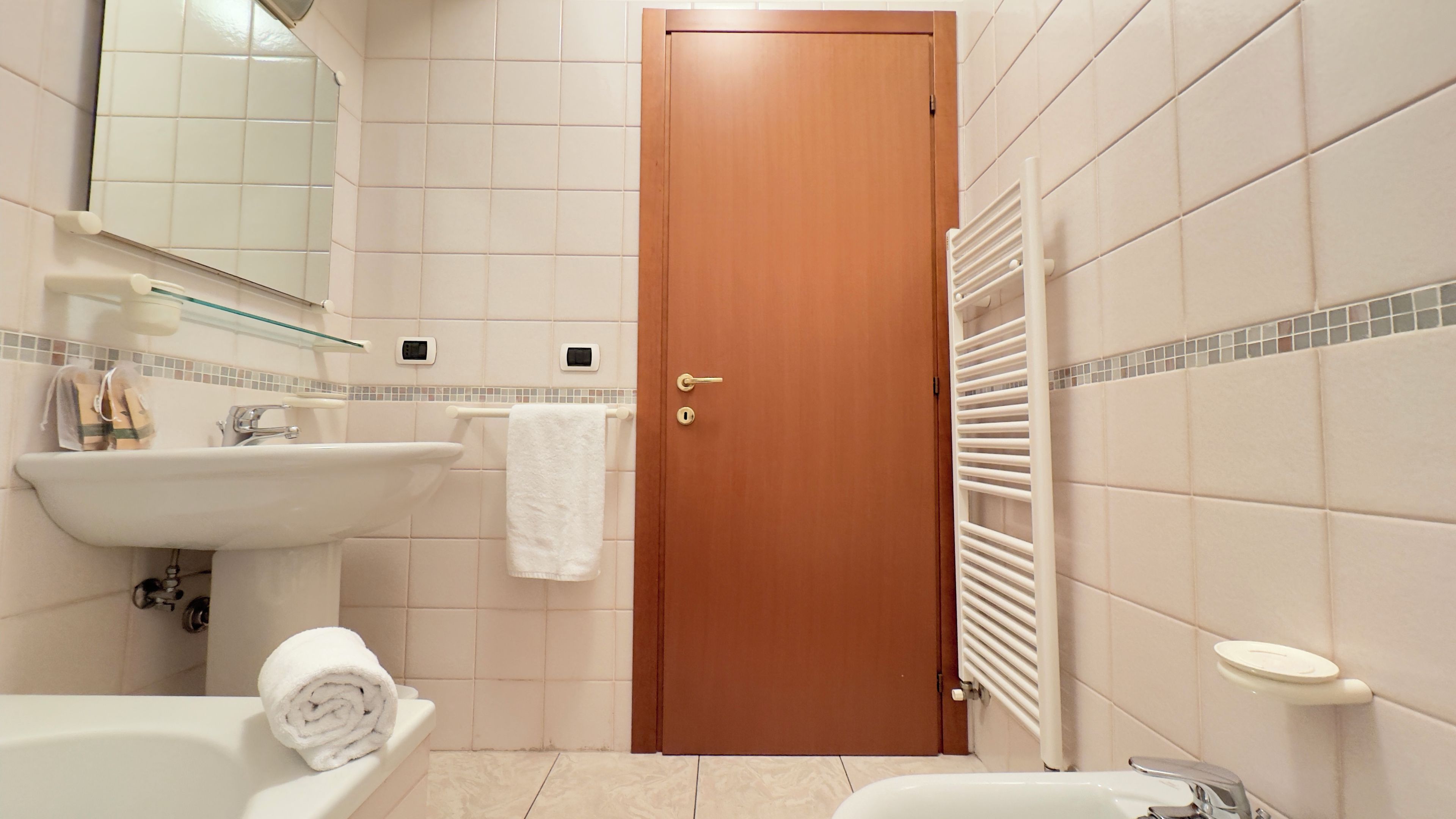 A bathroom with a wooden door, a white sink, a toilet, and a towel on the counter.