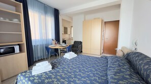 A hotel room with a bed, a desk, a chair, a wardrobe, and a microwave. - Le Due Farfalle by Ca-sa Check (Chioggia)
