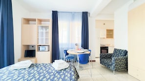 A hotel room with a bed, a desk with a chair, a kitchenette, and a bathroom. - Le Due Farfalle by Ca-sa Check (Chioggia)