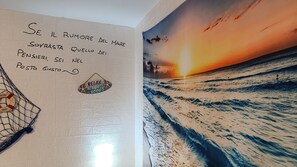 A wall with a sunset painting and a sign that reads "Se il rumore del mare sovrasta quell del pensiero, sei nel posto giusto." - Alicetta Apartment by Ca-sa Check (Chioggia)