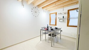 Un comedor con una mesa dispuesta para cuatro personas, techo de madera y una ventana con cortinas.