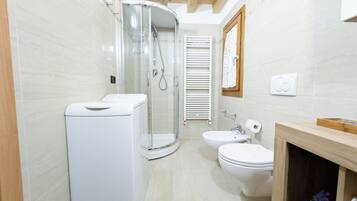 Uma casa de banho moderna com cabine de chuveiro em vidro, sanita e lavatório.