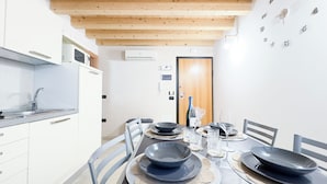 A modern kitchen with white cabinets, a stainless steel sink, and a wooden ceiling. - Romantic Flower by Ca-sa Check (Chioggia)