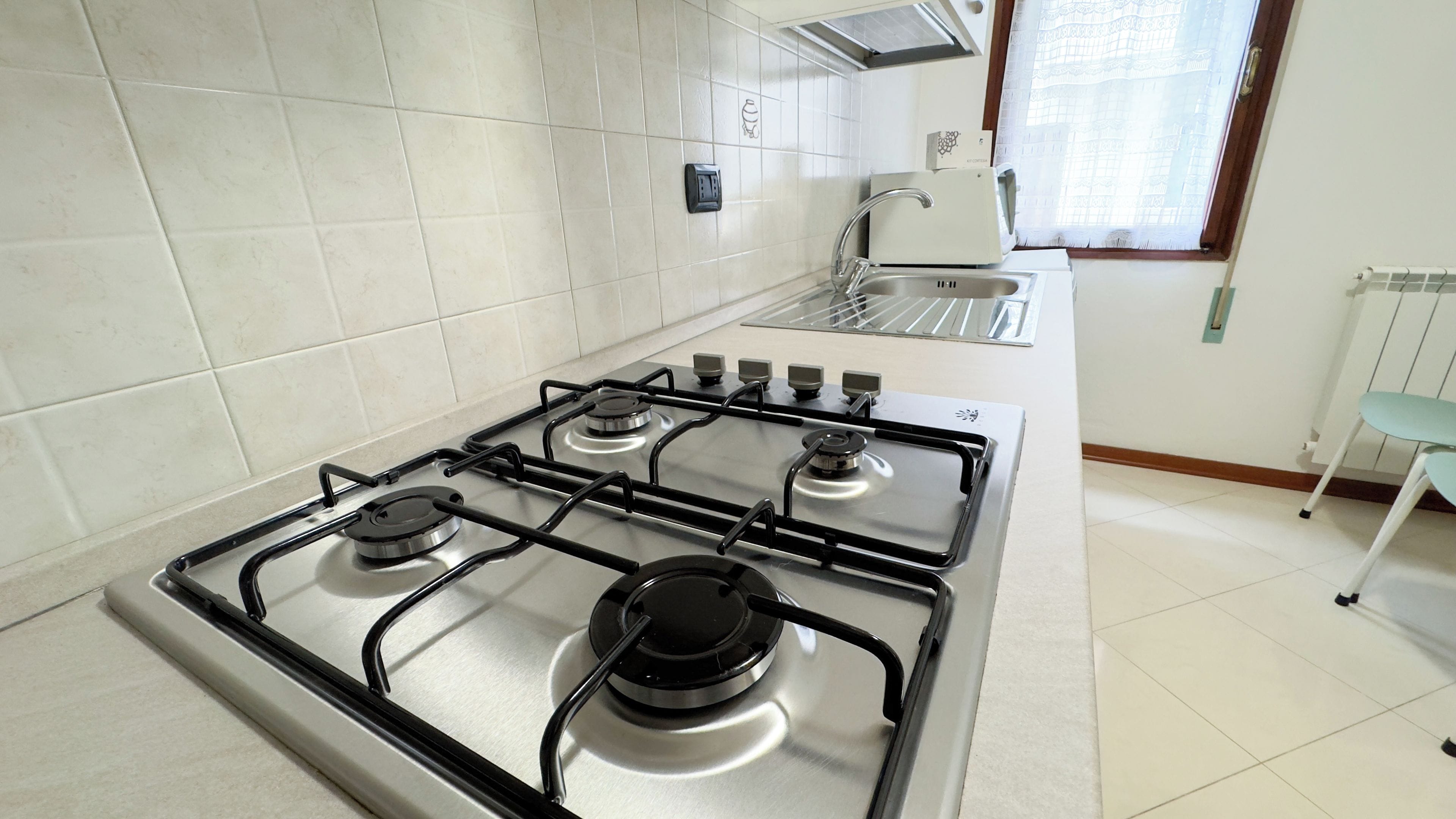 Een keuken met een gasfornuis, een magnetron en een spoelbak.