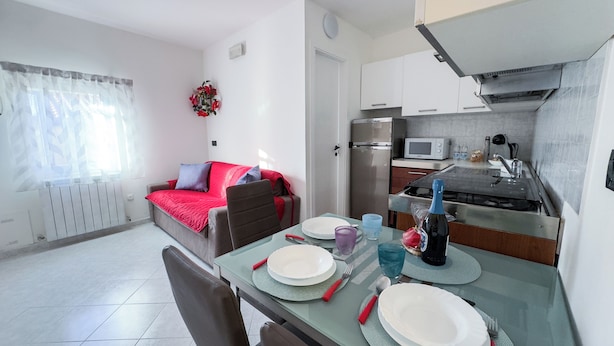 Eine moderne Wohnung mit Essbereich, Küchenzeile und Wohnzimmer mit Sofa und einem dekorativen Wandbild.