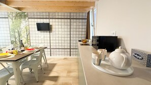 Cozinha moderna com área de refeições, televisão na parede e micro-ondas sobre a bancada.