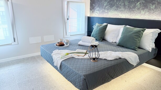 Een moderne slaapkamer met een groot bed, een raam en een kunstwerk aan de muur.