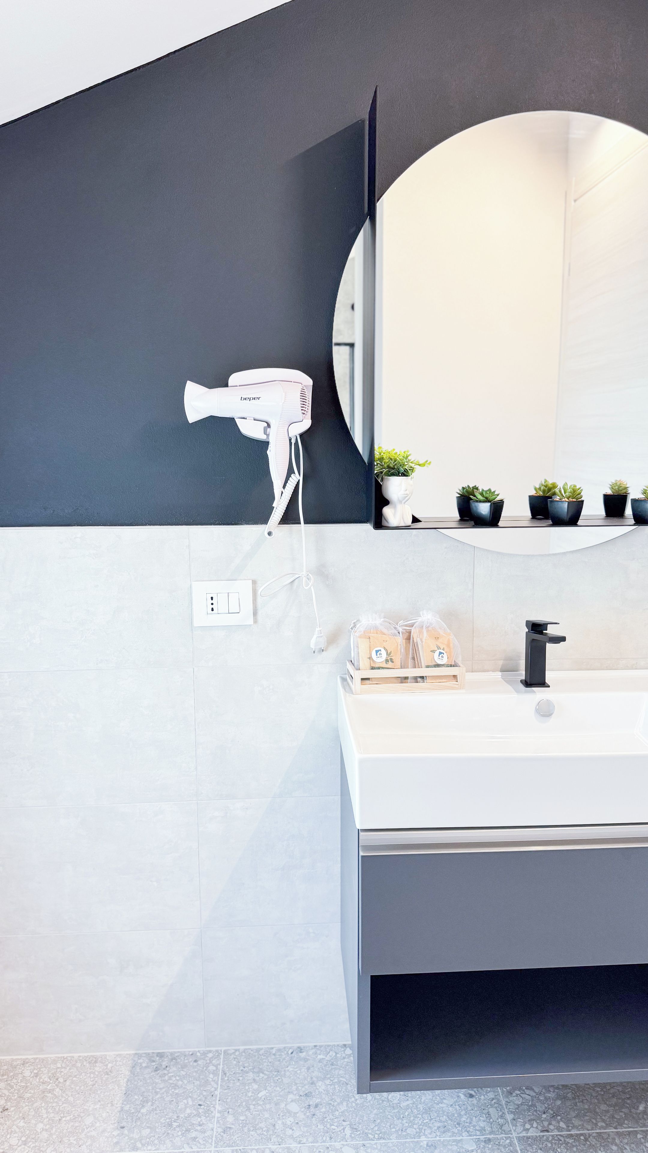Un baño moderno con lavamanos blanco, secador de pelo y espejo.