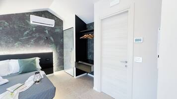 Quarto moderno com cama, mesa de cabeceira e ar condicionado fixado na parede.