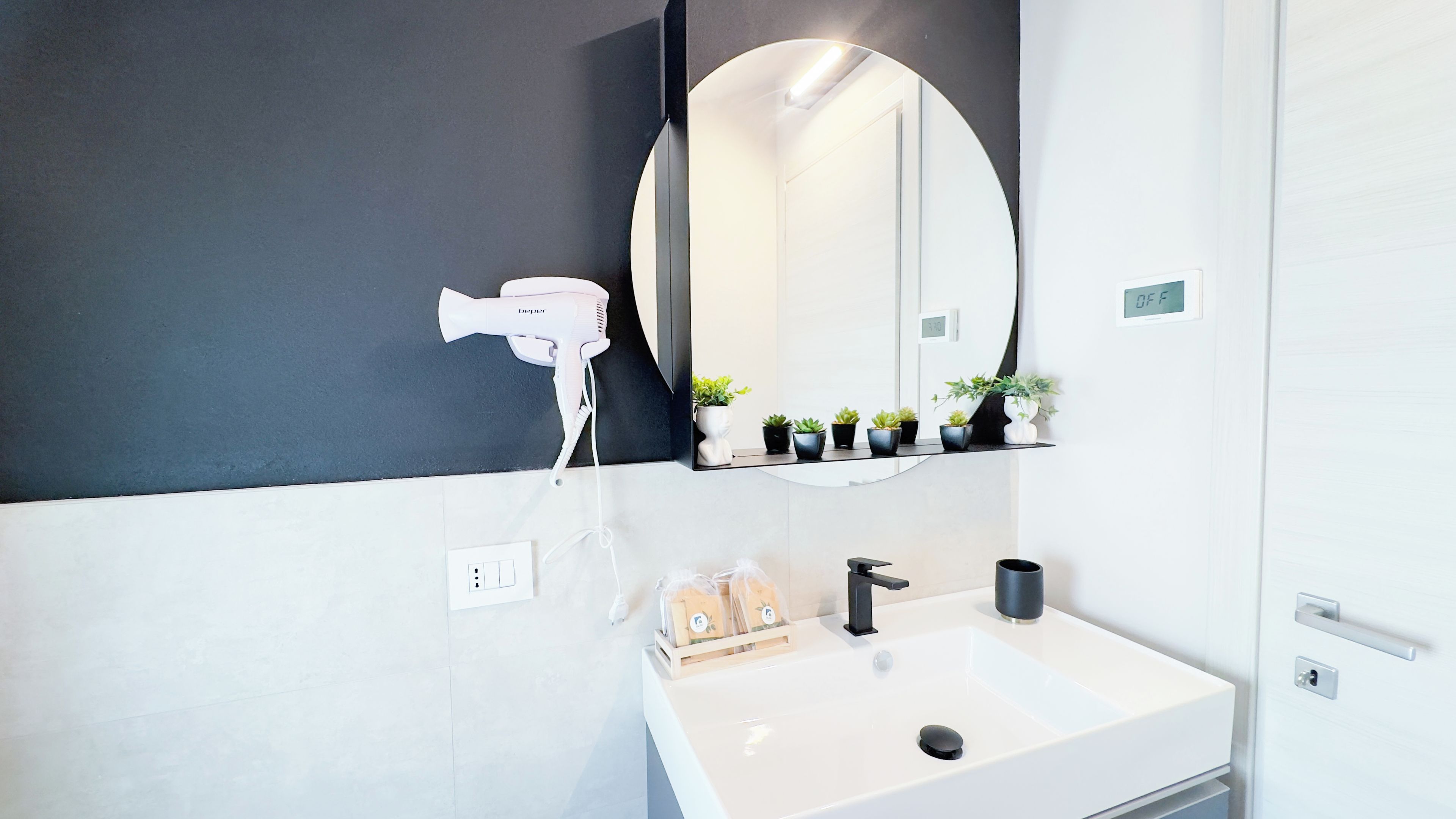 A modern bathroom with a white sink, a hairdryer, and a mirror.