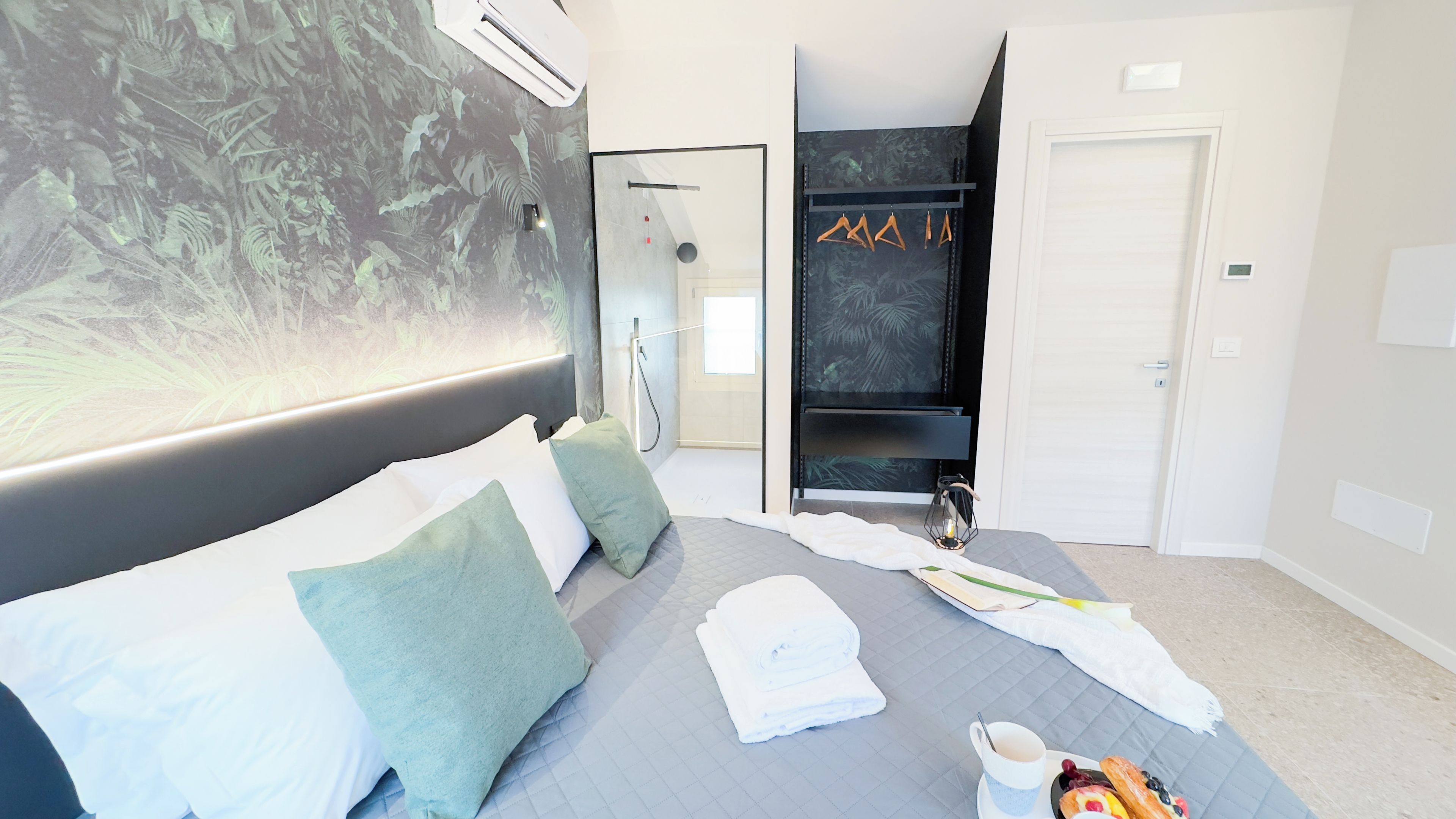 Una habitación de hotel moderna con cama, zona de ducha y armario.