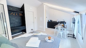 Een moderne hotelkamer met een bed, een kitchenette, een eethoek en een zithoek.