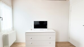 A white dresser with drawers and a flat-screen TV on top, positioned against a white wall with a radiator below. - Maison la Digue by Ca-sa Check (Chioggia)
