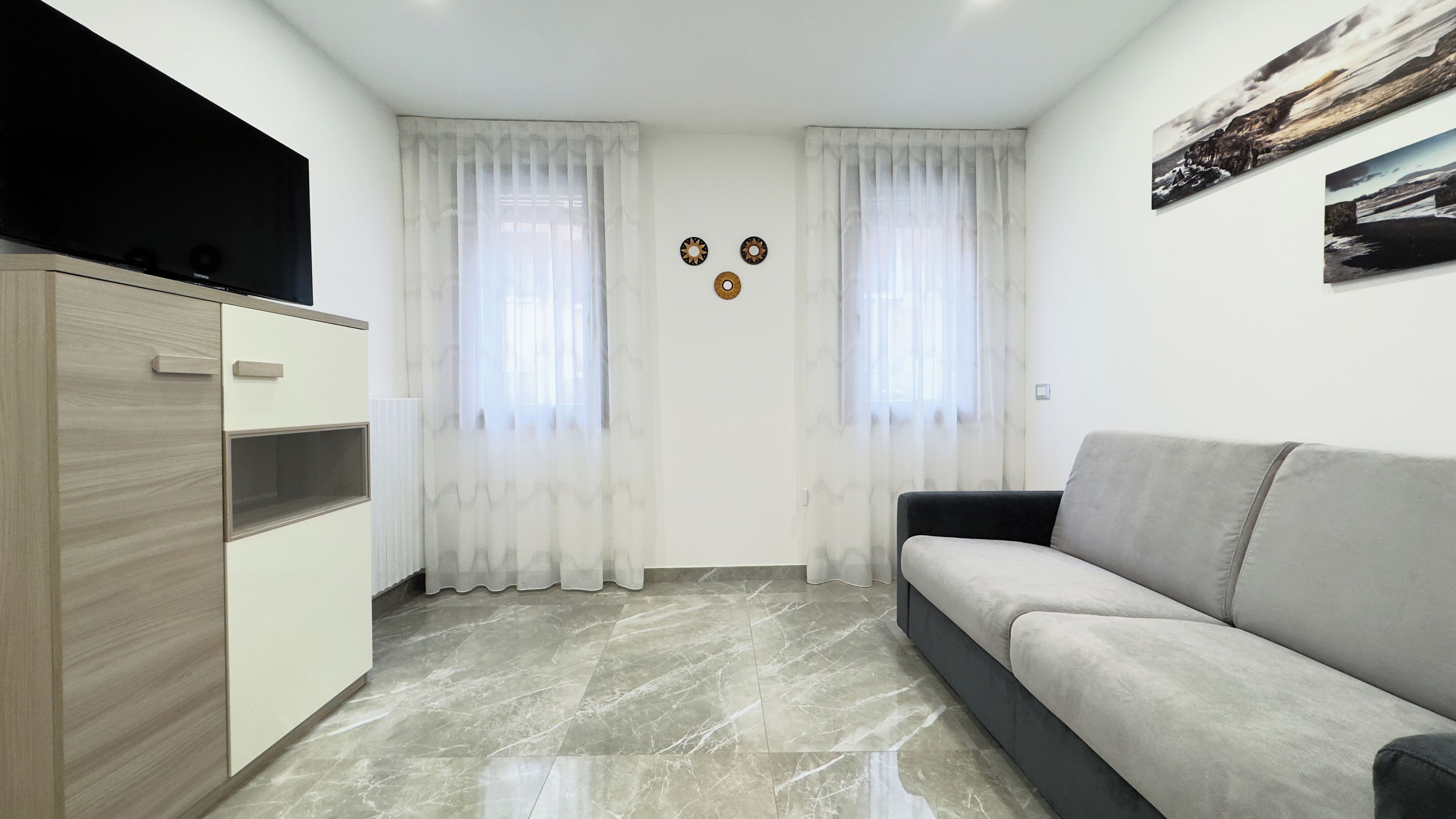 Una sala moderna con un sofá, un televisor y un aparador.