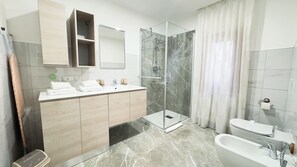 Un baño moderno con ducha envuelta en vidrio, tocador con espejo y bañera.