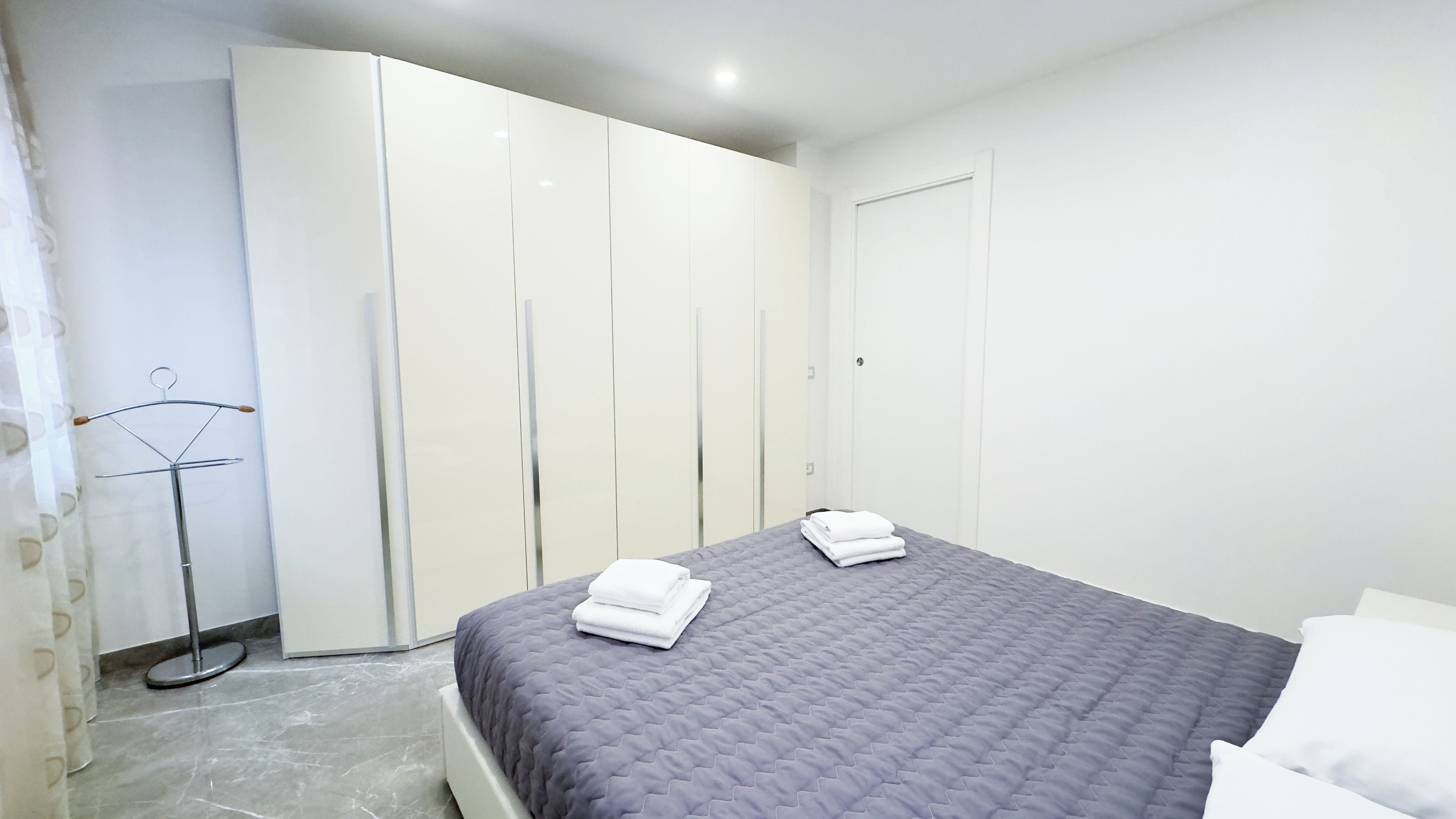 A bedroom with a bed, a wardrobe, and a mirror.