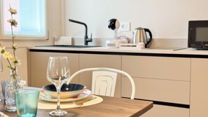 Una cocina moderna con una mesa de comedor para dos personas, una cafetera y una tetera en la encimera.