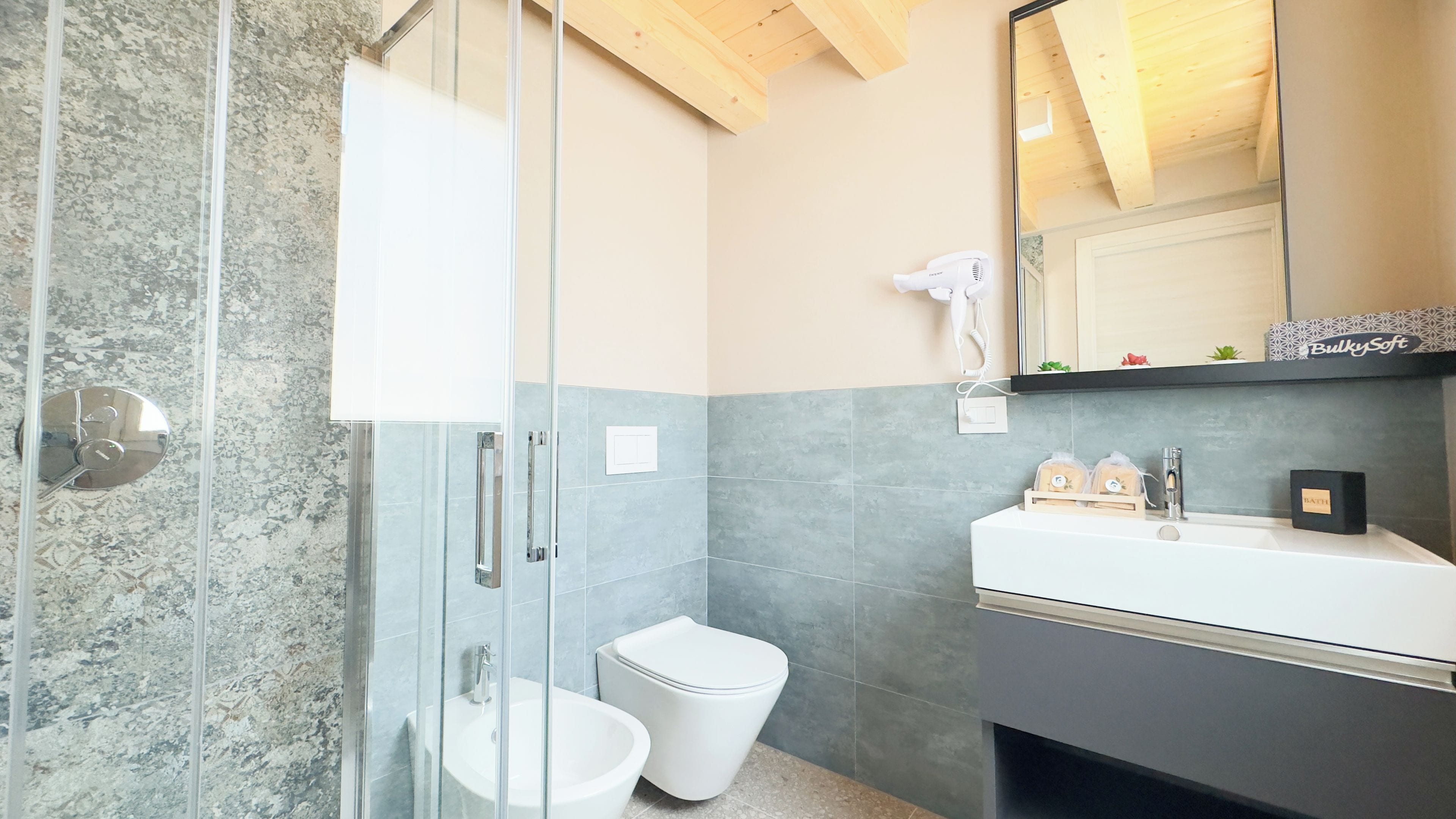Une salle de bain moderne avec une douche à parois de verre, des toilettes blanches et un meuble-lavabo avec un miroir.