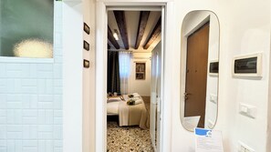 A hotel room with a bed, a small table with a tray, a mirror, and a door. - Gesuiti Cozy and Central Apartment by Ca-sa Check (Venice)