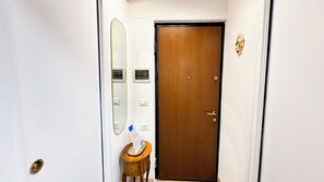 Ein Hotelzimmer mit Holztür, einem kleinen Tisch mit Spiegel und einem wandmontierten Lichtschalter.