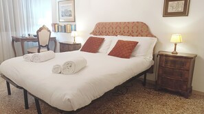A neatly made bed with rolled towels, a patterned headboard, and a small bedside table with a lamp. - Gorgeous Apartment St. Mark Square by Ca-sa Check (Venice)