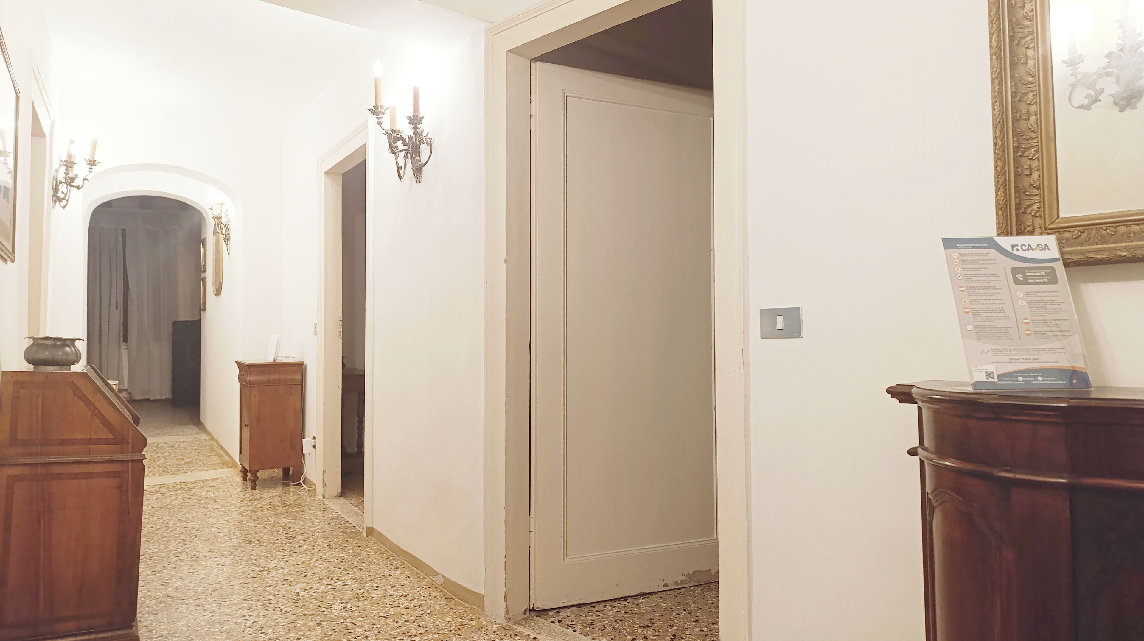 A hallway with a wooden cabinet, a door, and a wall-mounted sign.