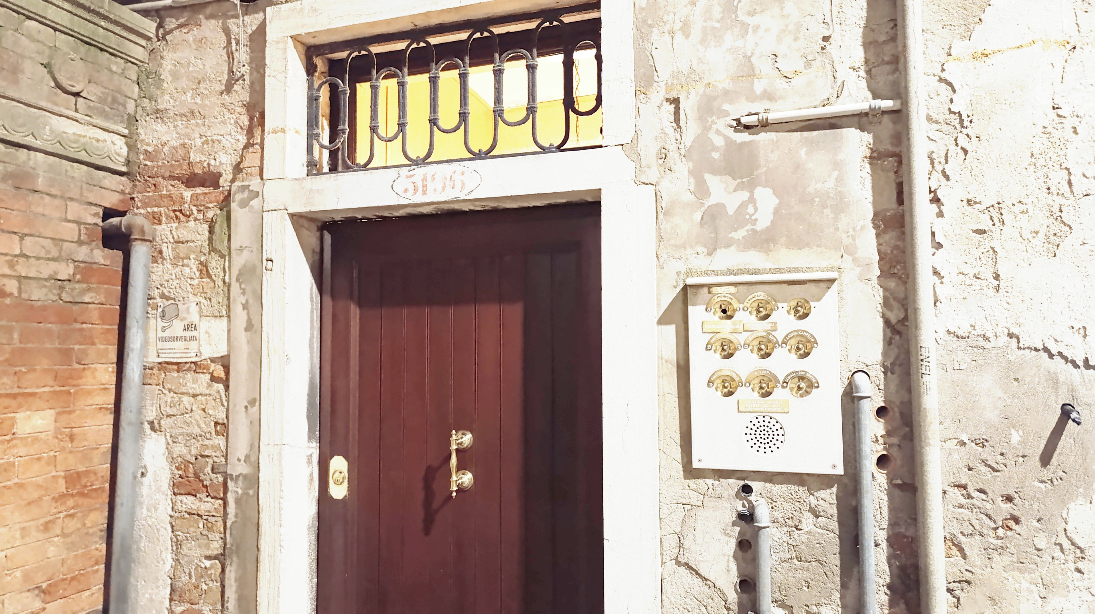 A building with a dark brown door, a sign above the door, and a utility box with multiple switches.