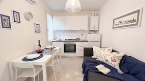 A compact living space with a dining area, kitchenette, and a sofa with a floral pillow. - Maison De La Brodeuse by Ca-sa Check (Chioggia)