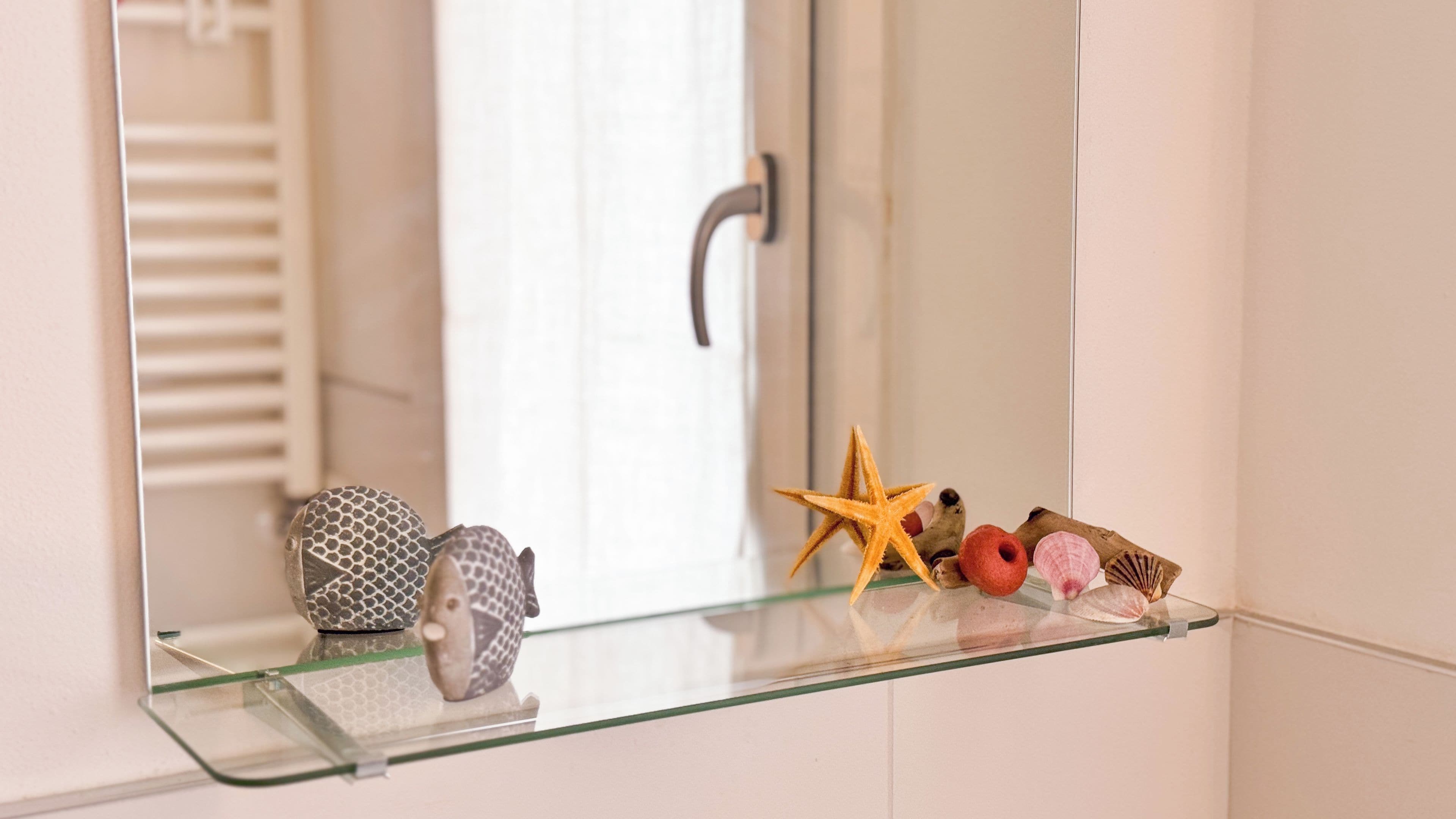 A bathroom with a glass shelf holding decorative items.