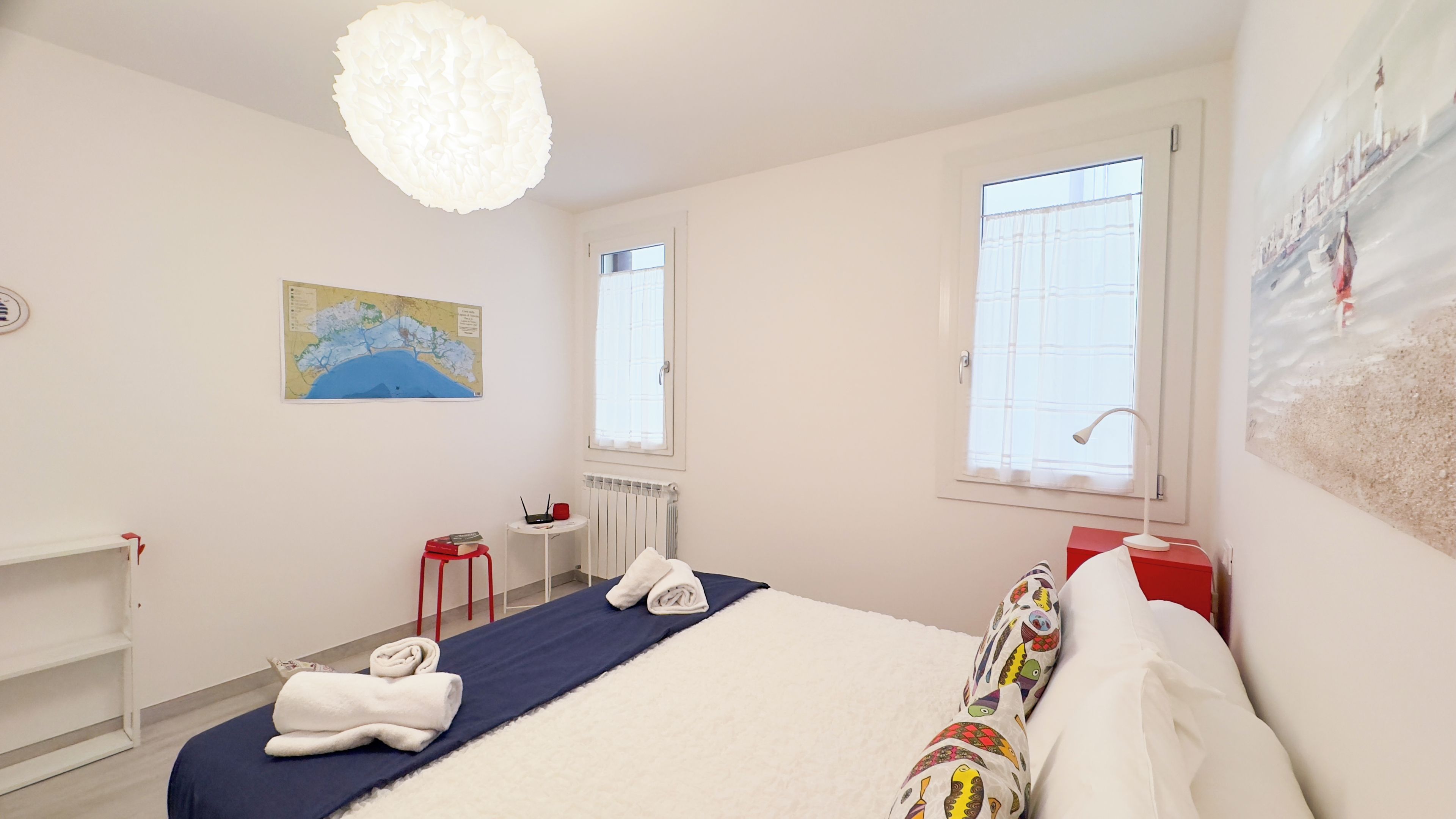 Una habitación de hotel con una cama, un mapa en la pared, una ventana y un radiador.