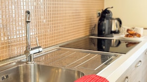 A kitchen with a stainless steel sink, a tiled backsplash, and a coffee maker on the counter. - Graceful Venice Barnaba Suite by Ca-sa Check (Venice)
