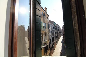 A narrow street with buildings on either side, a clear sky, and a person walking in the distance. - Apartment in the Heart of Venice by Ca-sa Check (Venice)