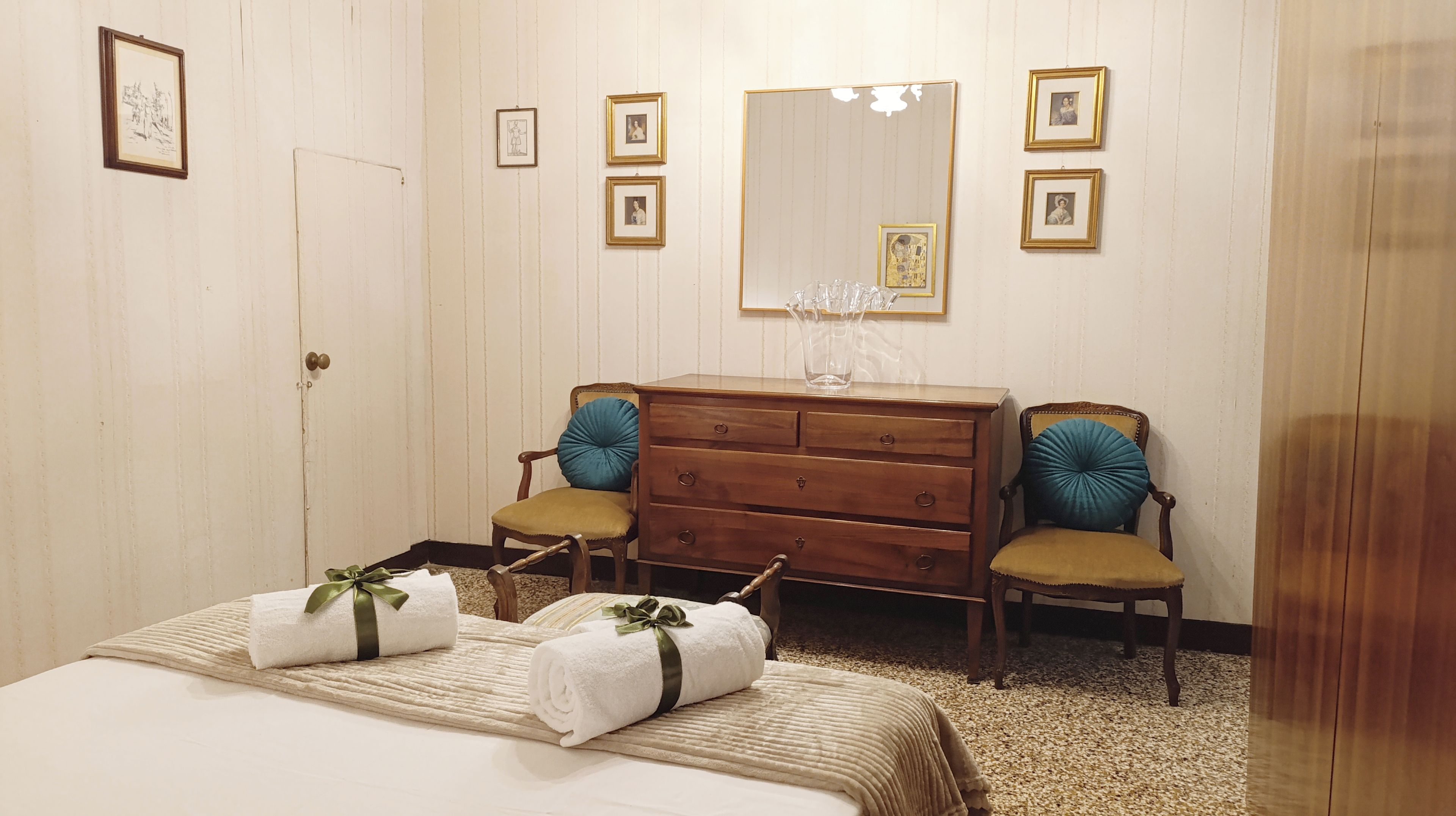 Ein Hotelzimmer mit einem Bett, zwei Stühlen, einer Holzkommode und einem Spiegel.