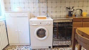 A compact kitchen with a washing machine, a stove, and a small refrigerator. - Apartment Near Biennale Theatre by Ca-sa Check (Venice)