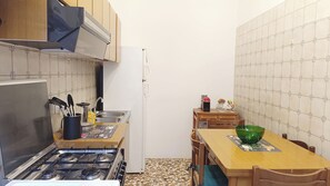 A compact kitchen with a gas stove, sink, and a small dining table with chairs. - Apartment Near Biennale Theatre by Ca-sa Check (Venice)