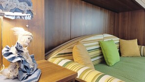 A room with a wooden headboard, a bed with striped bedding, a green pillow, and a small table with a decorative item. - Apartment Near Biennale Theatre by Ca-sa Check (Venice)